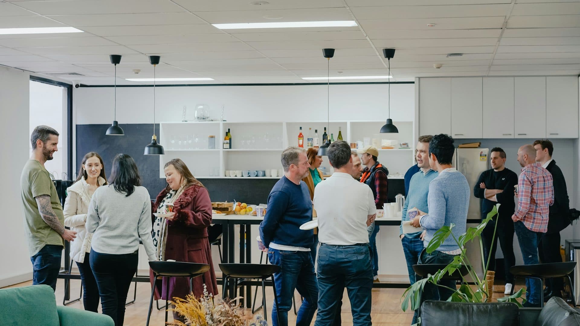 Des personnes qui discutent debout, un café à la main, lors d'un événement dans un espace de travail