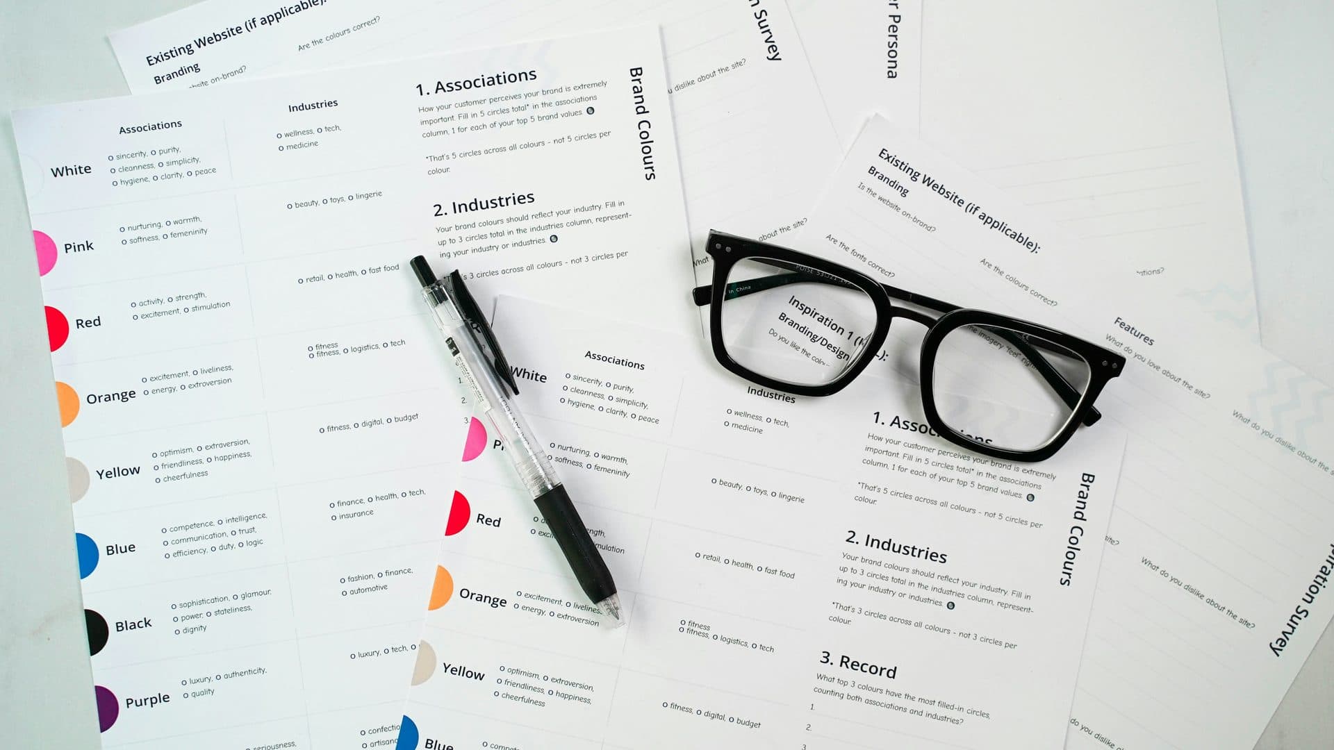 Feuilles de travail imprimées étalées sur une table, avec un stylo et une paire de lunettes